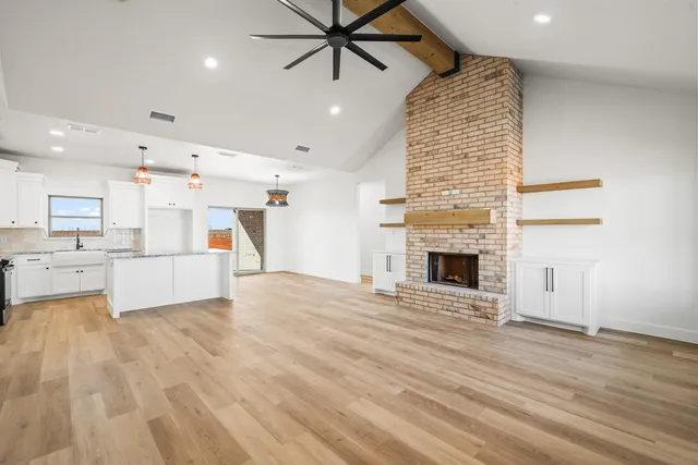 a view of a kitchen with kitchen island a sink wooden floor and a fireplace