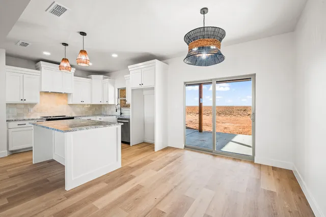 a kitchen with granite countertop a stove a refrigerator and a wooden floors
