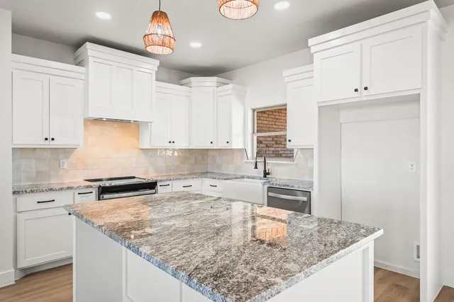 a kitchen with granite countertop a sink a stove and cabinets