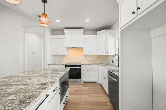 a large kitchen with granite countertop a stove top oven a sink a counter space and cabinets