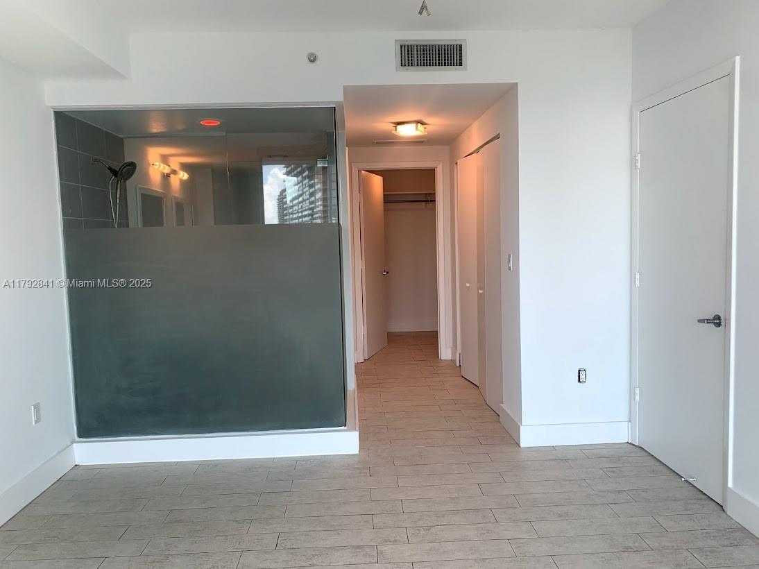 92 Southwest 3rd Street, Unit 3903 Miami, FL 33130 - Photo 7 of 25 an empty room with wooden floor and mirror