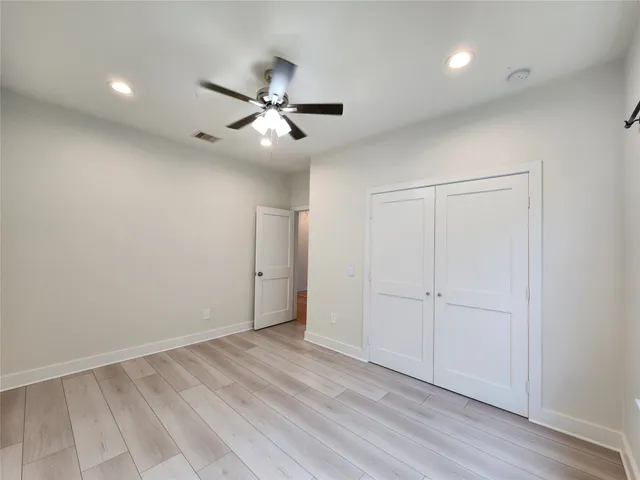 an empty room with wooden floor closet and fan