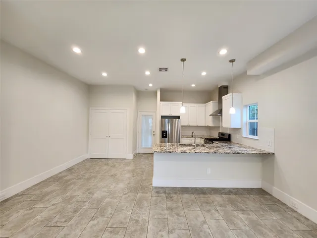 a large white kitchen with a large counter top space a sink stainless steel appliances and cabinets