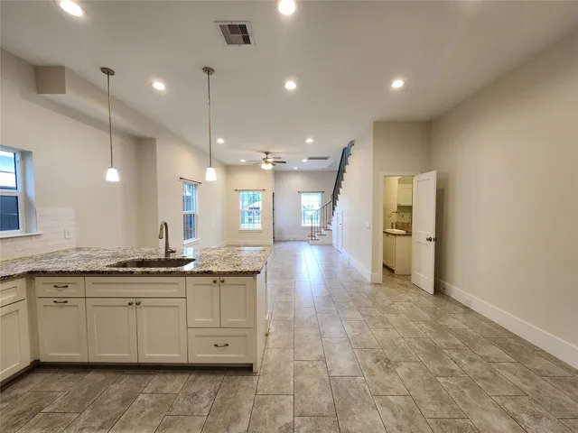 a large kitchen with granite countertop a sink and cabinets