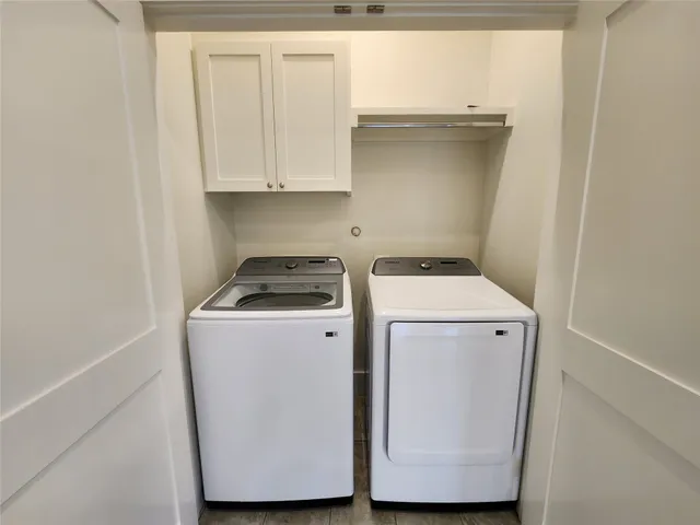 a utility room with wooden floor washer and dryer