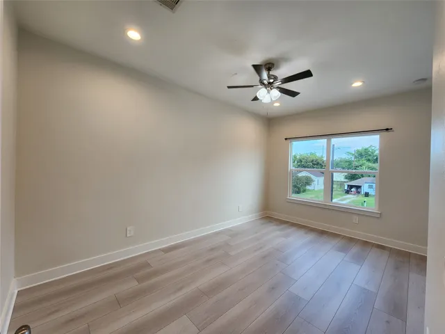 an empty room with wooden floor and ceiling fan