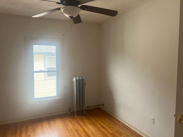 25 Ridge Street Middletown, NY 10940 - Photo 7 of 10 Unfurnished room with light wood-style flooring, radiator heating unit, and a ceiling fan