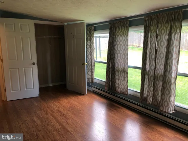 an empty room with wooden floor and windows with curtains view