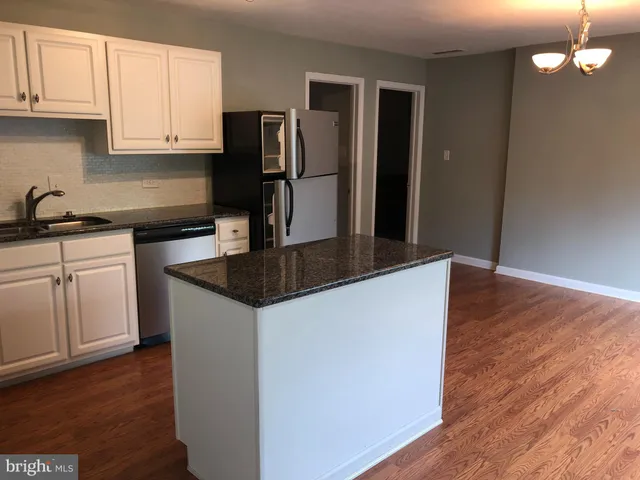 a kitchen with stainless steel appliances granite countertop a refrigerator a stove and a wooden floors