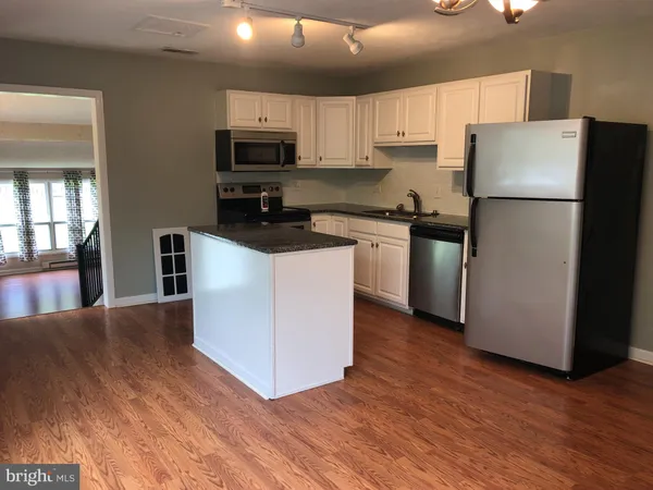 a kitchen with granite countertop a refrigerator stove top oven and sink