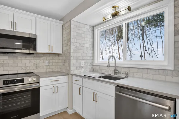a kitchen with stainless steel appliances granite countertop white cabinets and a stove top oven