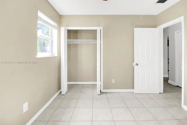 a view of an empty room with closet and a window