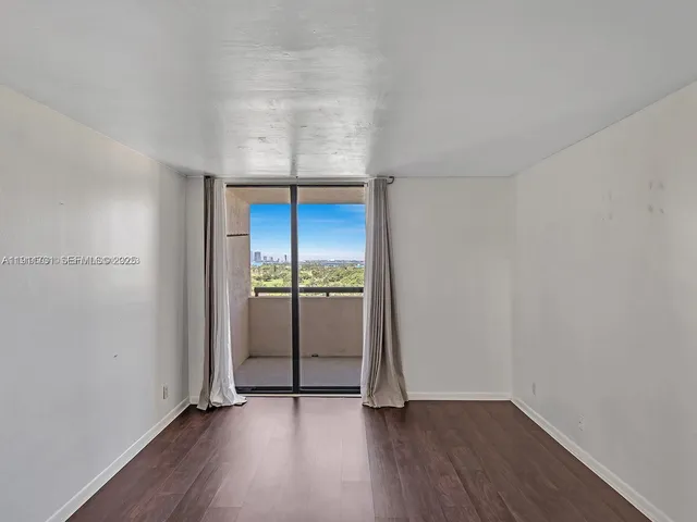 an empty room with wooden floor closet and windows