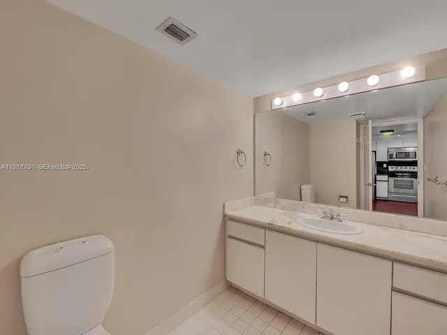 a spacious bathroom with a granite countertop sink a toilet and a mirror