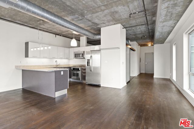 a large kitchen with stainless steel appliances granite countertop a large counter top a wooden floors and a fireplace