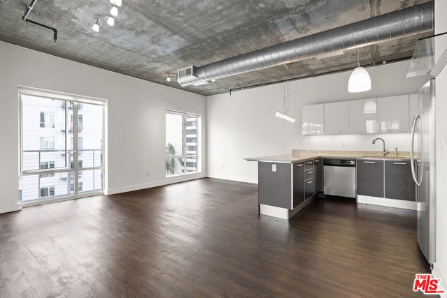 a large kitchen with stainless steel appliances granite countertop a large counter top and a wooden floors