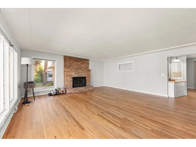 a big room with wooden floor and fireplace