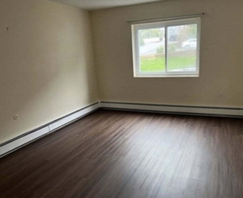 12 Cox Court, Unit 2 Beverly, MA 01915 - Photo 5 of 8 an empty room with wooden floor and windows