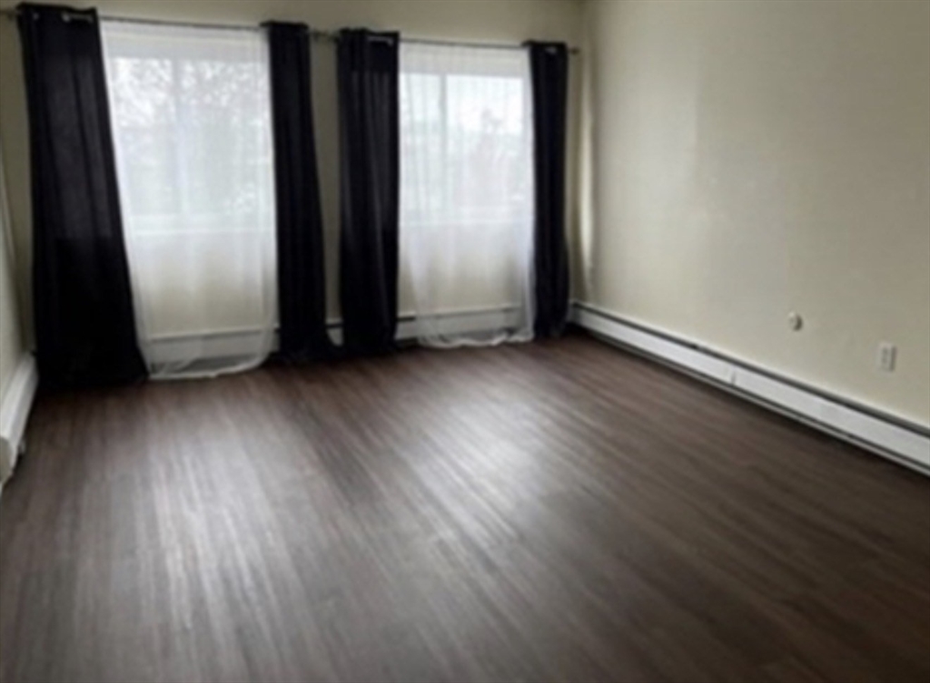 12 Cox Court, Unit 2 Beverly, MA 01915 - Photo 8 of 8 an empty room with wooden floor and windows