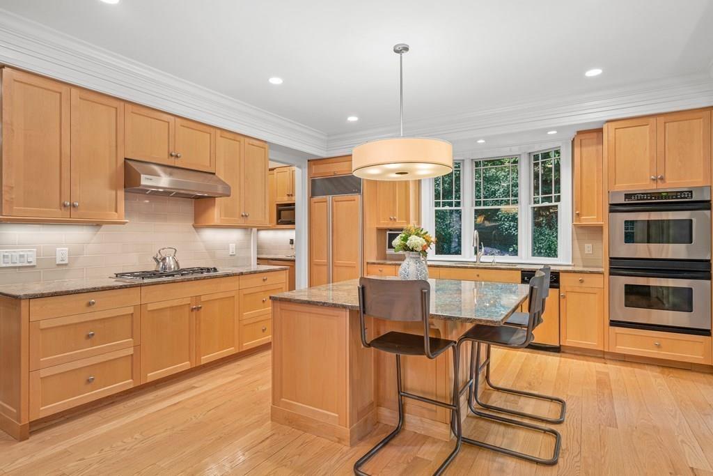 150 Wellesley Street Weston, MA 02493 - Photo 8 of 31 a kitchen with stainless steel appliances granite countertop a stove top oven a sink dishwasher a dining table and chairs with wooden floor