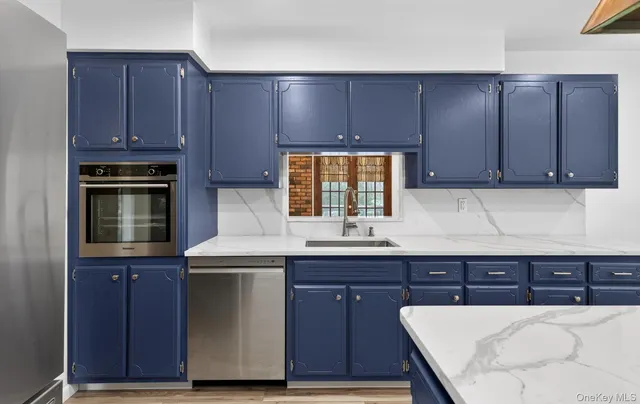 a kitchen with stainless steel appliances a stove a refrigerator and a dining table with wooden floor