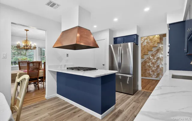 a kitchen with stainless steel appliances kitchen island granite countertop a table chairs in it and wooden floors