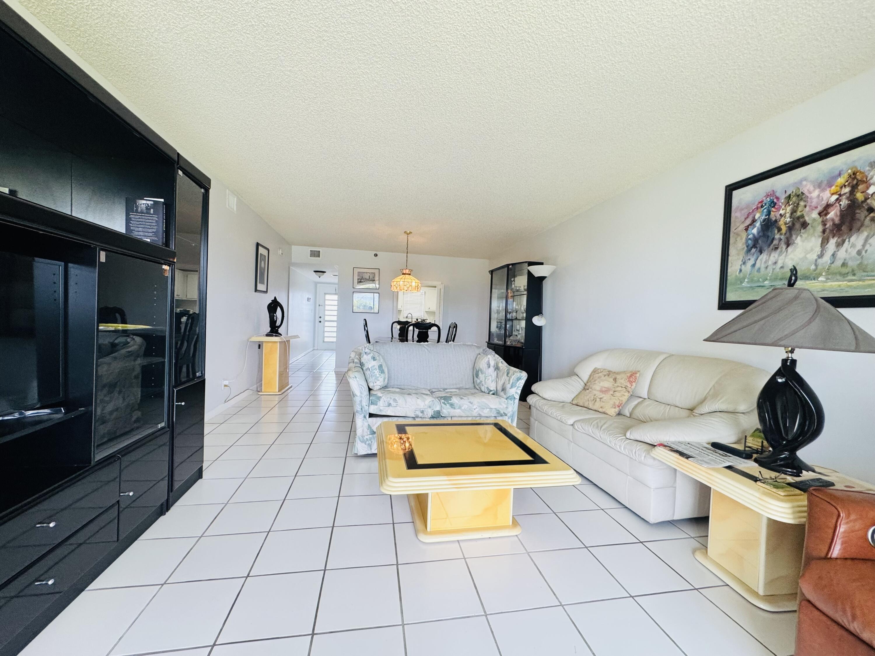 2430 DC Country Club Boulevard, Unit 4072 Deerfield Beach, FL 33442 - Photo 7 of 28 a living room with furniture a flat screen tv and a floor to ceiling window