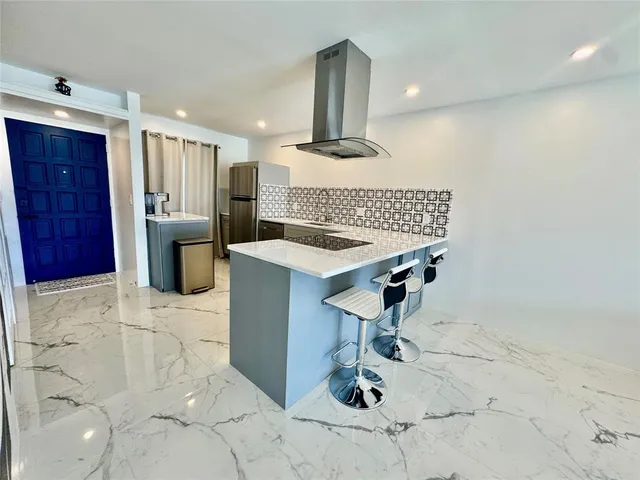 a kitchen with stainless steel appliances kitchen island granite countertop a sink and a refrigerator
