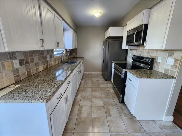 a kitchen with stainless steel appliances granite countertop a stove a sink and a microwave