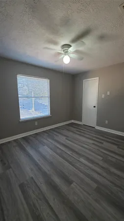 an empty room with wooden floor chandelier fan and windows