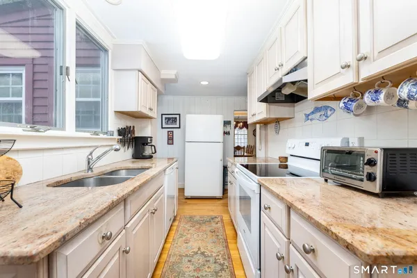 a kitchen with stainless steel appliances granite countertop a sink a stove and a refrigerator