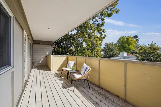 a balcony with wooden floor table and chairs