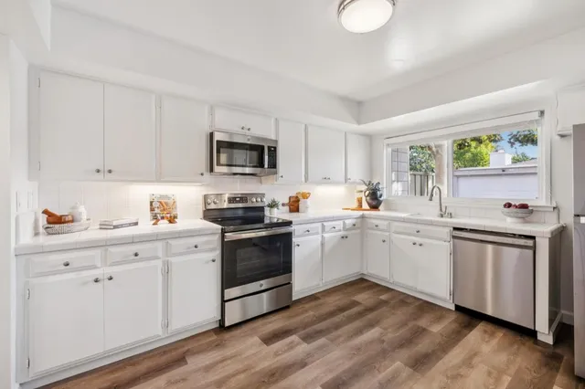 a kitchen with granite countertop white cabinets and white appliances