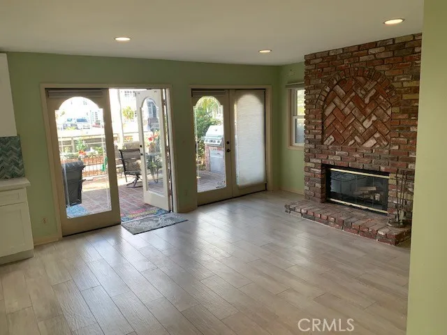 an empty room with wooden floor fireplace and windows