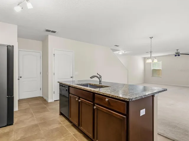 a kitchen with stainless steel appliances granite countertop a sink dishwasher and a refrigerator with wooden cabinets
