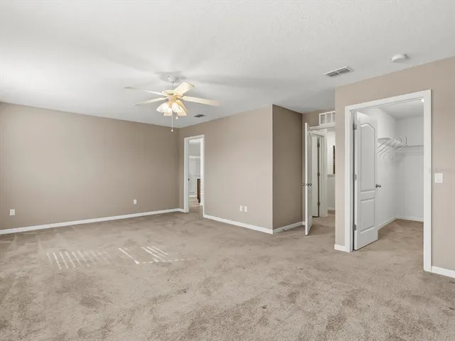 an empty room with chandelier fan and closet area