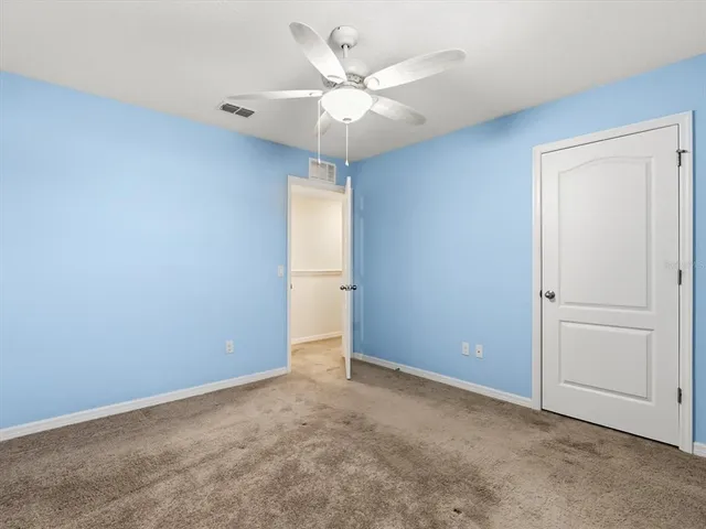 an empty room with closet and ceiling fan