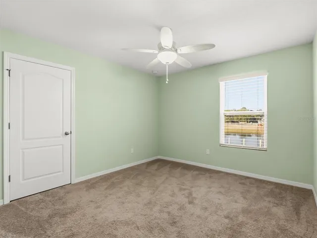 an empty room with a ceiling fan and window