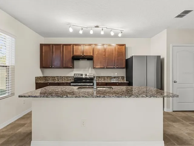 a kitchen with stainless steel appliances granite countertop a sink refrigerator and cabinets
