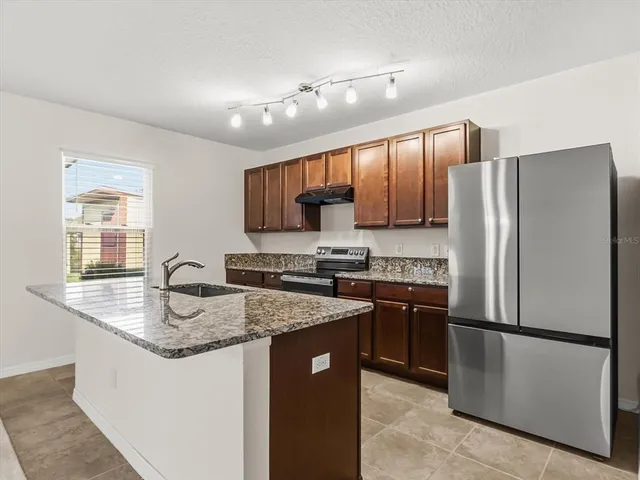 a kitchen with stainless steel appliances granite countertop a sink refrigerator and microwave
