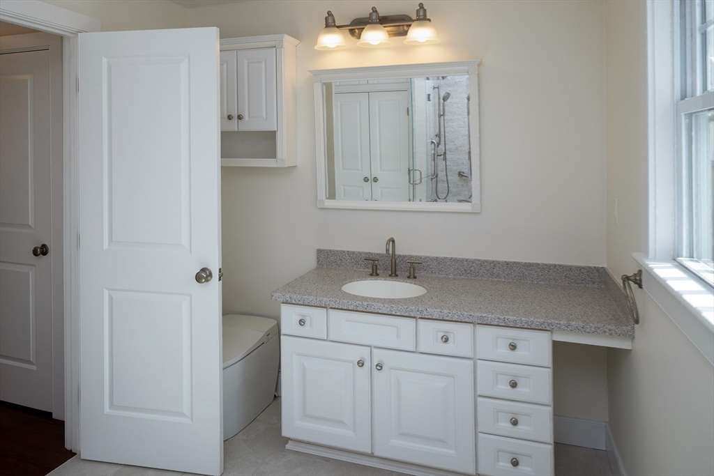 9 Meade Avenue, Unit 1 Hull, MA 02045 - Photo 26 of 34 a bathroom with a granite countertop sink and a mirror