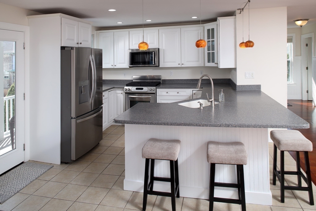 9 Meade Avenue, Unit 1 Hull, MA 02045 - Photo 9 of 34 a kitchen with stainless steel appliances granite countertop a stove a refrigerator a sink a table and chairs
