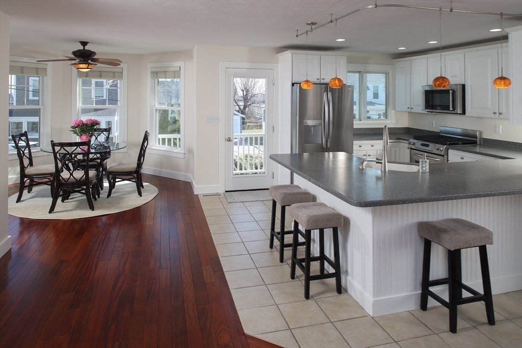 9 Meade Avenue, Unit 1 Hull, MA 02045 - Photo 10 of 34 a kitchen with stainless steel appliances granite countertop a stove a refrigerator a kitchen island a dining table and chairs with wooden floor