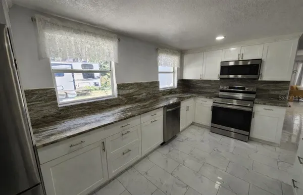 a kitchen with stainless steel appliances granite countertop a stove sink and microwave