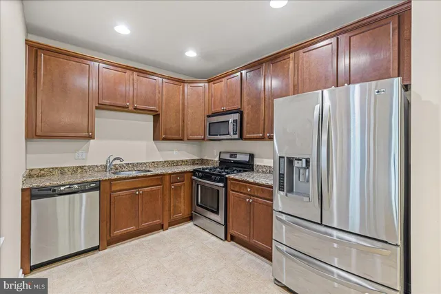 a kitchen with granite countertop stainless steel appliances cabinets and a refrigerator