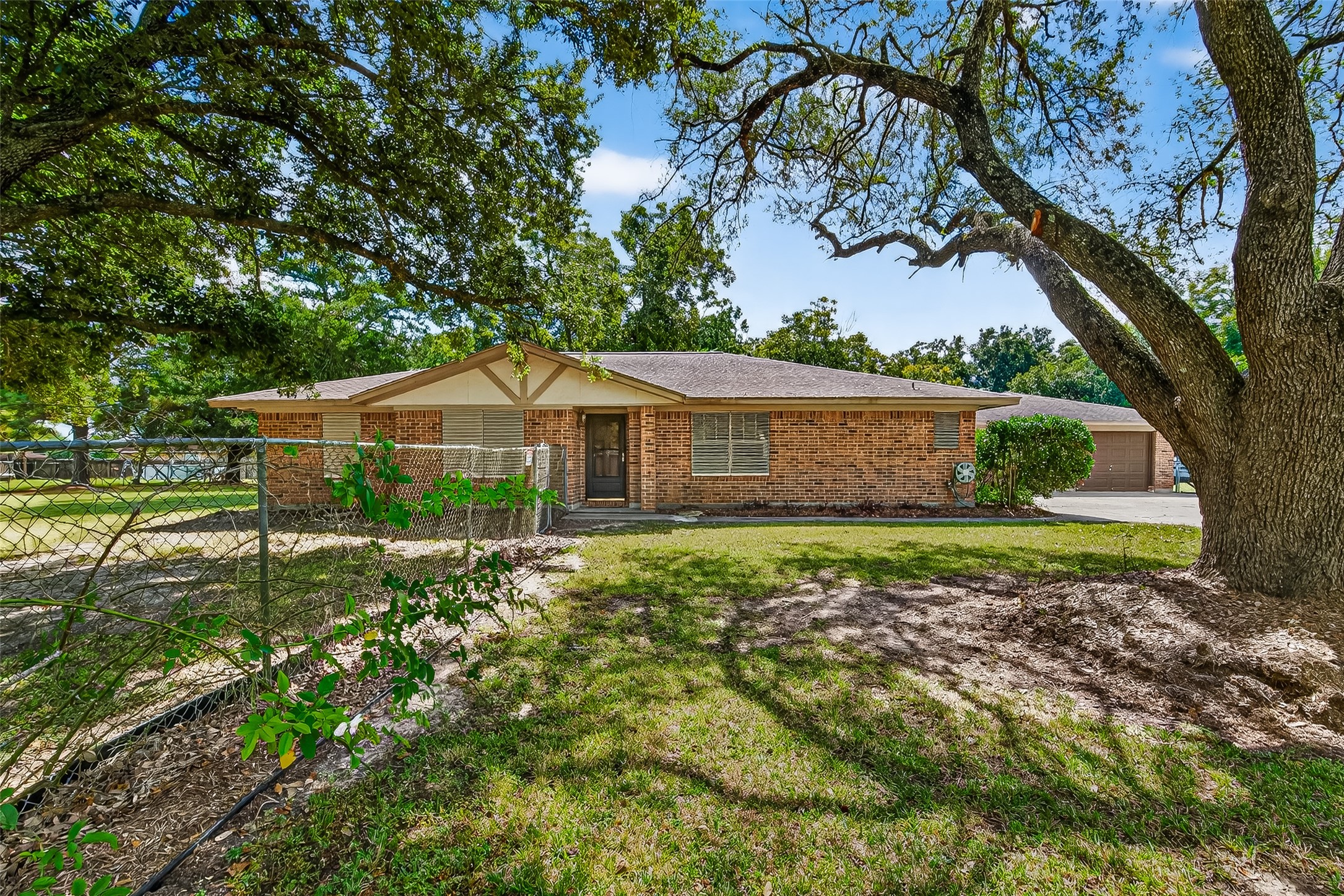 12021 7th 1/2 Street Santa Fe, TX 77510 - Photo 3 of 49 Charming brick ranch-style home with a welcoming front entrance, nestled among mature trees. The spacious yard offers shade and privacy, perfect for outdoor activities. Ideal for those seeking a serene and inviting environment.