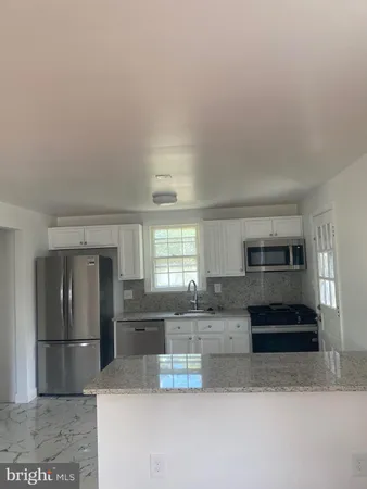 a kitchen with granite countertop a refrigerator and a stove top oven
