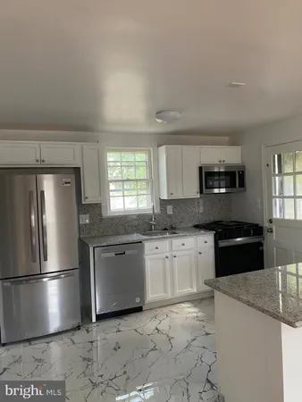 a kitchen with granite countertop a refrigerator stove top oven and sink