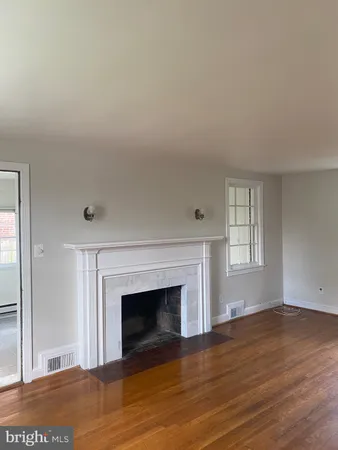 a view of empty room with wooden floor and fireplace