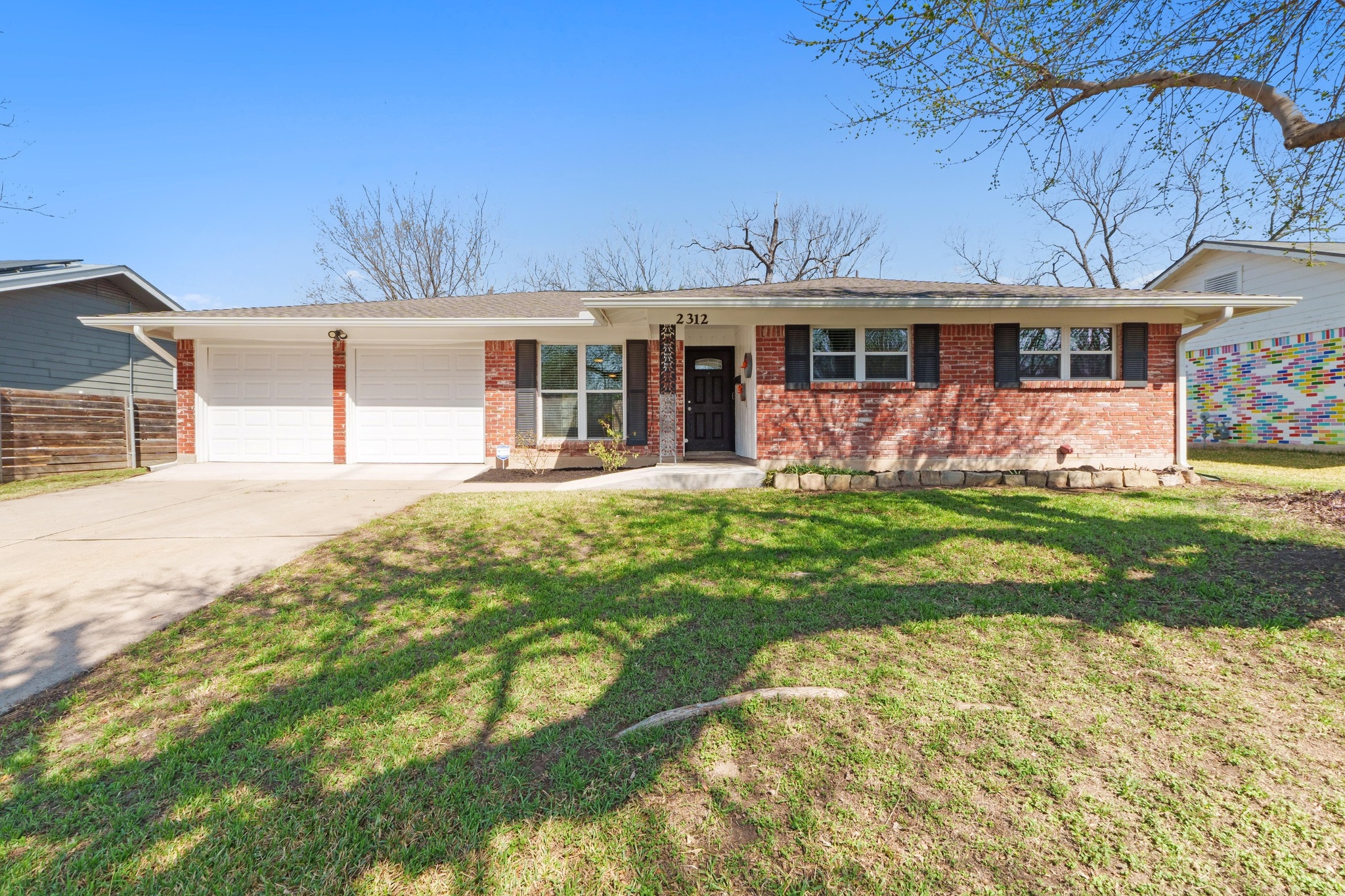 Single story home featuring an attached garage, concrete driveway, brick siding, and a front yard